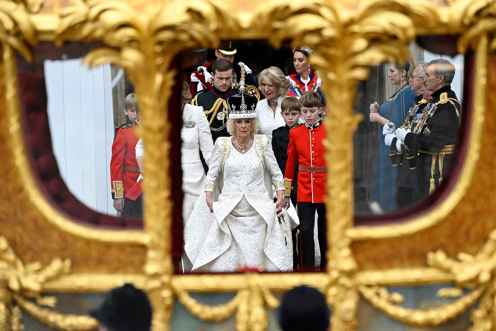 Kraliçe taç giyme töreni elbisesiyle.  Elbisenin üzerindeki işlemeler, Camilla'nın İngiliz kalp çelenklerine yakından benzeyen temaları temsil ediyor.