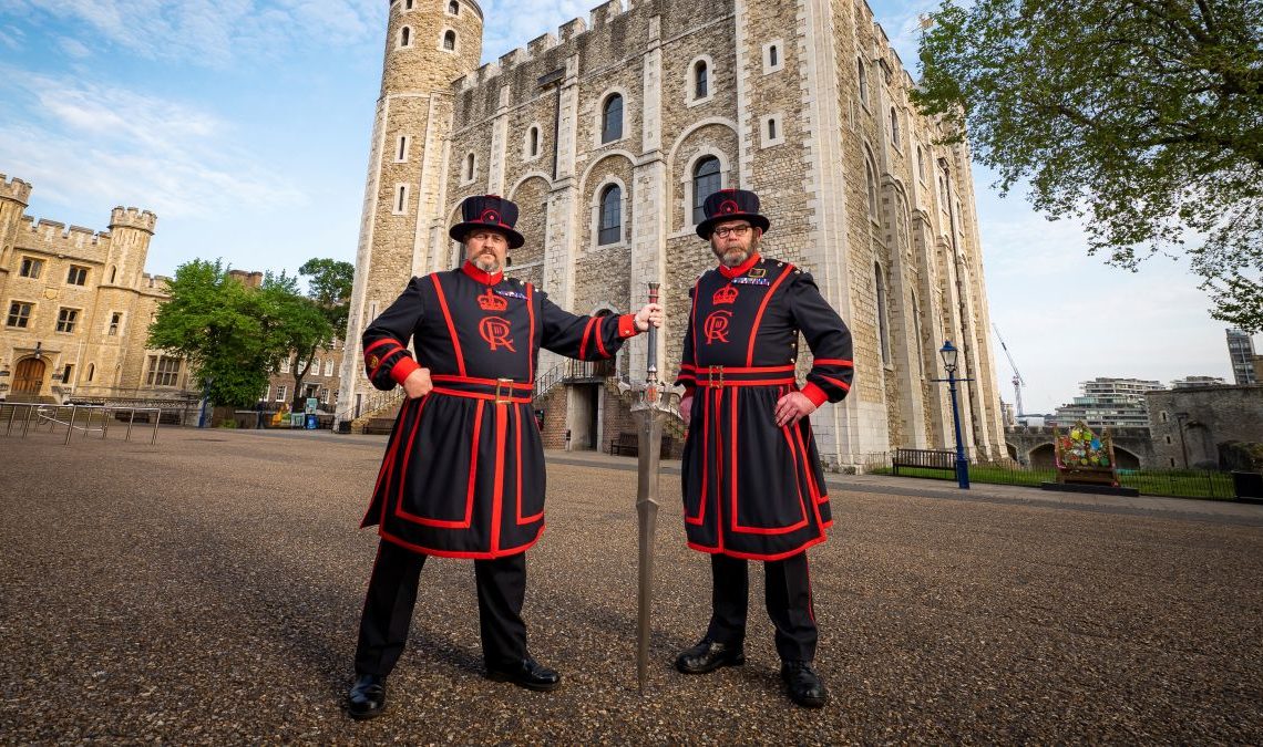 Two Beefeaters hold a Final Fantasy sword outside the Tower of London.